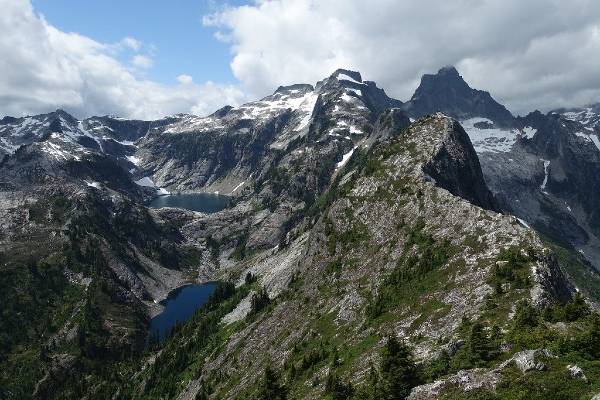 alt="פסגות-הרים-סלעיים-מושלגים-ואגם-מתחת-לצוקים-הפארק-הלאומי-צפון-קסקייד">