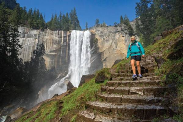 alt="אישה-יורדת-במדרגות-ברקע-מפל-הפארק-הלאומי-יוסמיטי">
