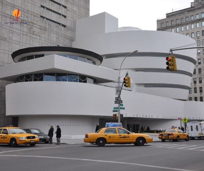 מבנה מוזיאון גוגנהיים (Solomon R. Guggenheim Museum) העגלגל והספירלי בשדרה החמישית בניו יורק, לצד רחוב סואן עם מוניות צהובות.