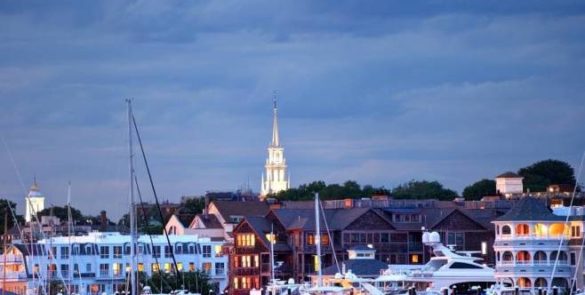 מבט מהים על קו החוף של ניופורט עם בתי אחוזה מפוארים ויאכטות עוגנות במהלך רוד טריפ בארה"ב