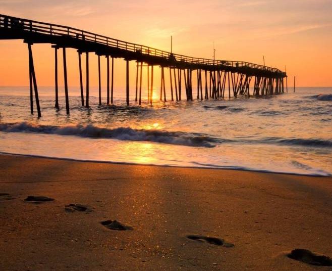 מזח עץ ארוך המשתרע אל תוך האוקיינוס האטלנטי בחופים החוליים של איי האאוטר בנקס (OBX), צפון קרוליינה.