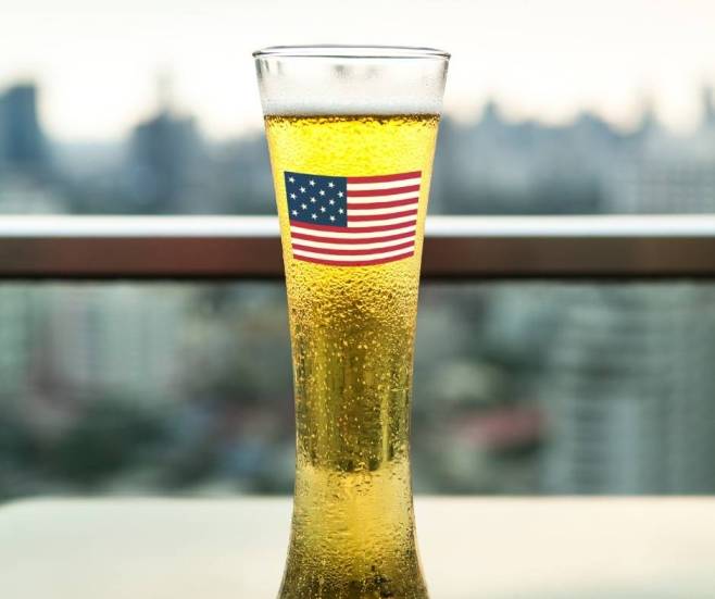 alt="בירה-עם-דגל-ארצות-הברית-מול-נוף-עירוני">