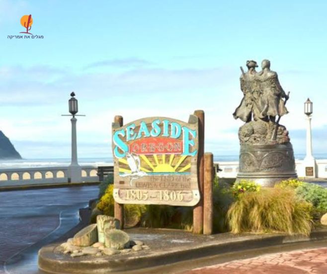 שלט העץ הצבעוני של העיירה סיסייד, אורגון (Seaside, Oregon), המציין את סוף נתיב משלחת לואיס וקלארק (The End of the Lewis and Clark Trail), לצד פסל הברונזה של החוקרים על רקע הטיילת והים.